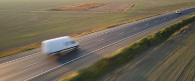 Aerial view of blurred fast moving cargo van driving on highway hauling goods. Delivery transportation and logistics concept.